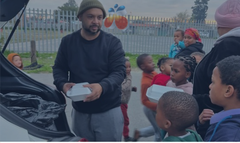 Café Mambo team handing out warm meals to children and families at a community outreach